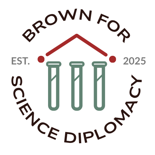 Circular logo reading “Brown for Science Diplomacy” around the border. Inside the circle are three stylized test tubes beneath a simple red roof shape, suggesting a building or institution. On either side of the central graphic are the words “EST.” and “2025” separated by small red dots. The design uses muted green, red, and brown tones on a dark background.