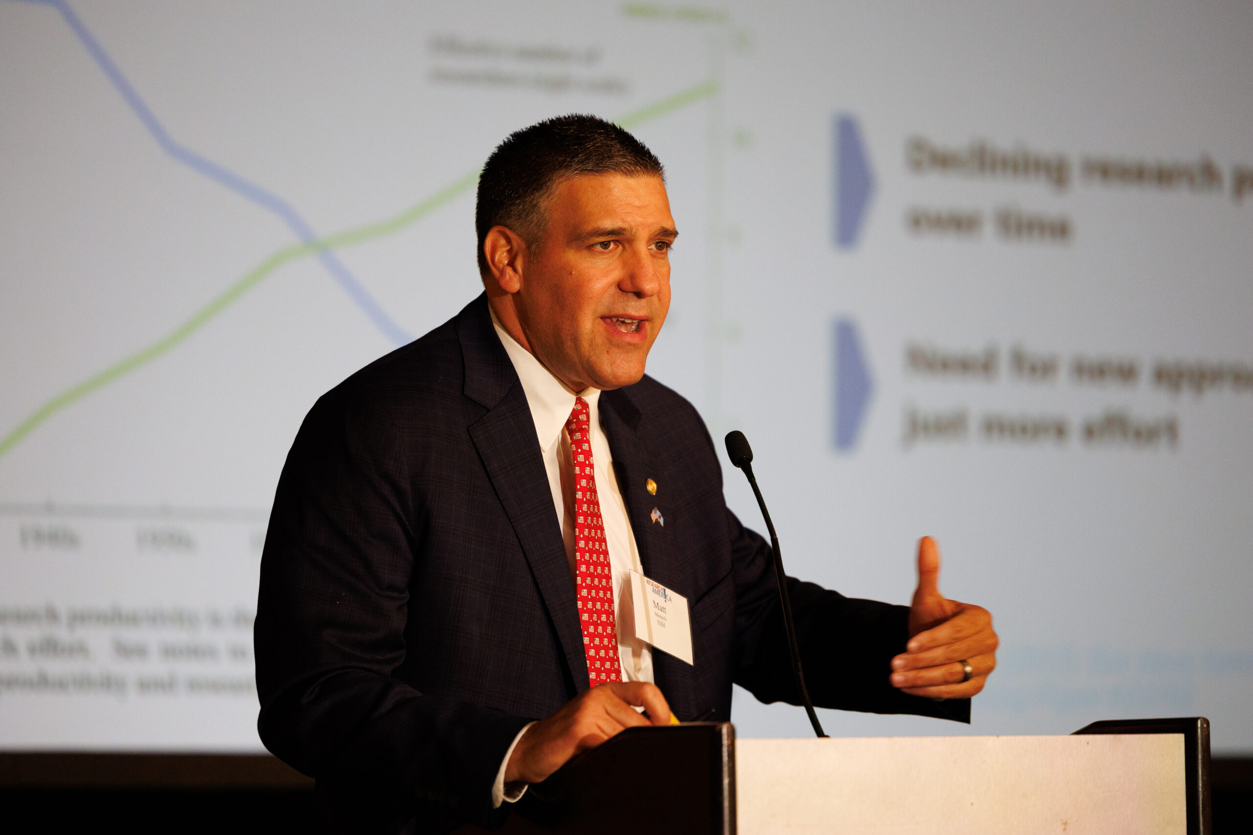 Matthew Memoli speaking from behind a podium at the 2026 National Health Research Forum
